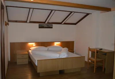 a bedroom with a large bed with a desk and a bed sidx sidx sidx sidx at Hotel Stella Alpina in Bellamonte