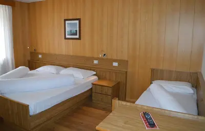 a bedroom with two beds and a remote control on a table at Hotel Stella Alpina in Bellamonte