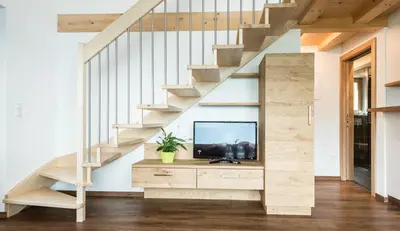 a living room with a tv under a staircase at Tallnerhof in Schenna