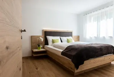 a bedroom with a bed with white walls and a window at Tallnerhof in Schenna