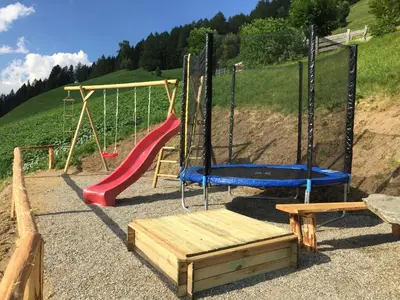 a playground with a slide and a swing at Tallnerhof in Schenna