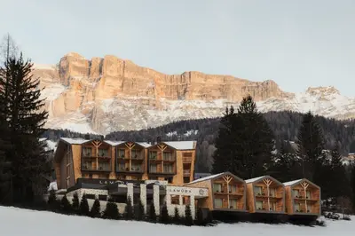 a building in the snow with a mountain in the background at Hotel La Müda in Badia