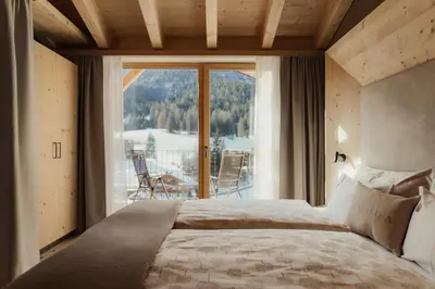 a bedroom with a bed and a large window at Hotel La Müda in Badia