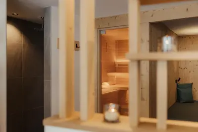 a bathroom with a sauna with a reflection in a mirror at Hotel La Müda in Badia