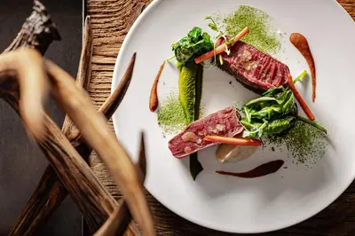 a plate of food with meat and vegetables on a table at Boutique Hotel Nives - Luxury & Design in the Dolomites in Selva di Val Gardena