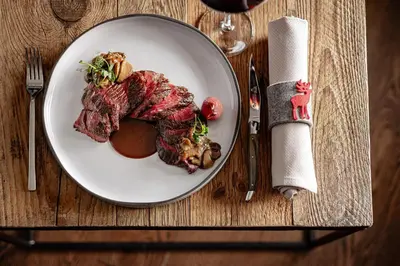 a plate of food with meat on a table at Boutique Hotel Nives - Luxury & Design in the Dolomites in Selva di Val Gardena