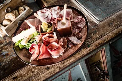 a plate of food with meat and cheese on a table at Boutique Hotel Nives - Luxury & Design in the Dolomites in Selva di Val Gardena