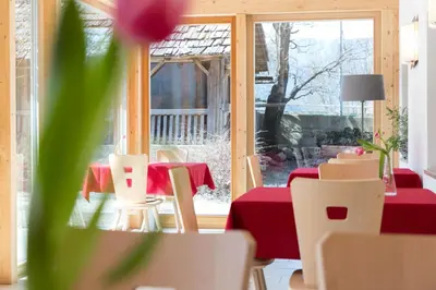 a dining room with a red table and chairs and a window at Garni Bachlerhof in Brunico