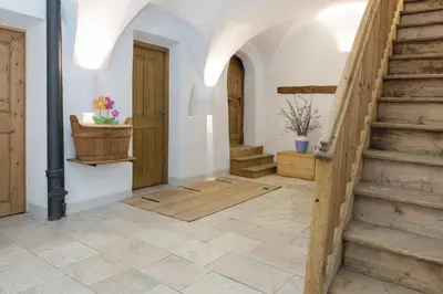 a hallway with wooden stairs and a potted plant at Garni Bachlerhof in Brunico