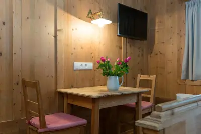 a wooden table with a vase of flowers on it at Garni Bachlerhof in Brunico
