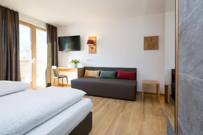 a hotel room with a bed and a couch at Garni Bachlerhof in Brunico