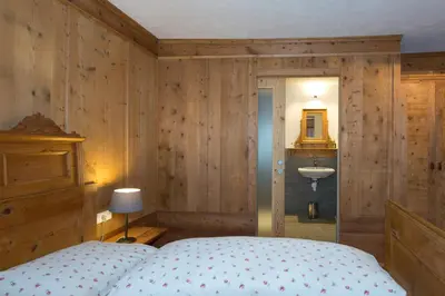 a bedroom with wooden walls and a bed and a sink at Garni Bachlerhof in Brunico