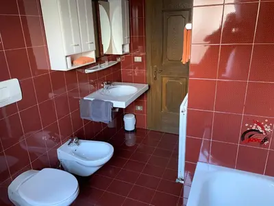 a red tiled bathroom with a toilet and a sink at Appartments Hilber in Brunico