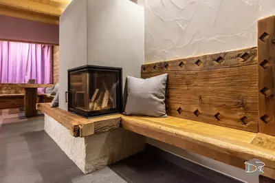 a living room with a bench with a fireplace at Casa de Fiemme in Tesero