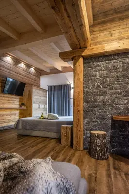a bedroom with a bed and a stone wall at Casa de Fiemme in Tesero