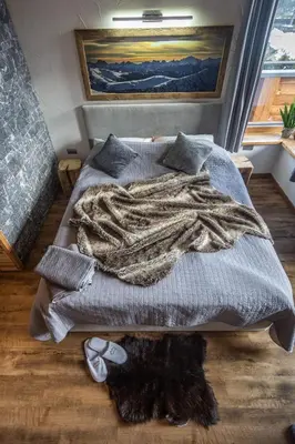 a bed with a blanket and a cat laying on the floor at Casa de Fiemme in Tesero