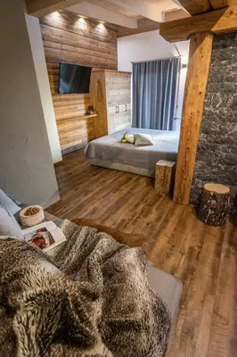 a room with a bed in a room with wooden floors at Casa de Fiemme in Tesero
