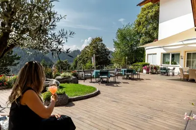 a woman sitting on a deck with a glass of wine at Hotel Marica in Eggen