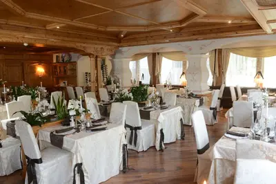 a dining room with white tables and chairs at Hotel Letizia in San Martino di Castrozza