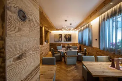 a restaurant with wooden walls and tables and chairs at Hotel Letizia in San Martino di Castrozza