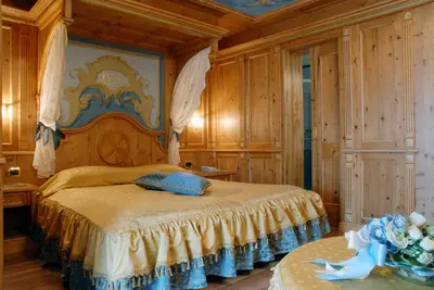 a bedroom with a large bed with wooden walls at Hotel Letizia in San Martino di Castrozza