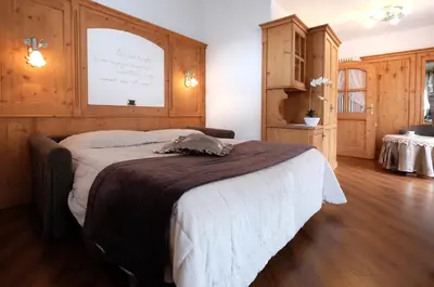 a bedroom with a bed with a board on the wall at Hotel Letizia in San Martino di Castrozza