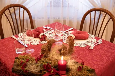 a table with a red table cloth with a candle at Albergo Conca Verde in Fiera di Primiero