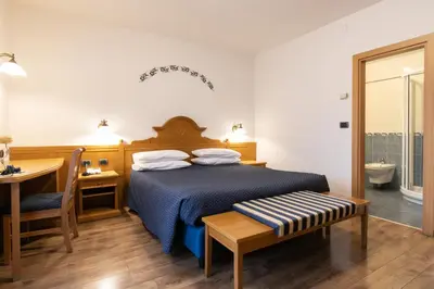 a bedroom with a bed and a desk and a table at Albergo Conca Verde in Fiera di Primiero
