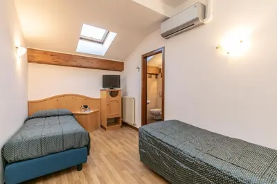 a hotel room with two beds and a television at Albergo Conca Verde in Fiera di Primiero