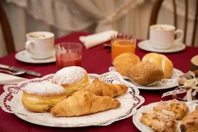 a table topped with plates of pastries and cups of coffee at Albergo Conca Verde in Fiera di Primiero