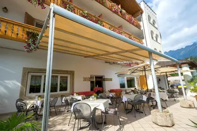 a patio with tables and chairs on a building at Hotel Marlingerhof in Marlengo