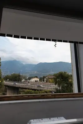 a window with a view of a bridge and mountains at Hotel Marlingerhof in Marlengo