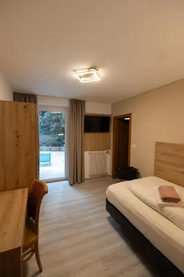 a bedroom with a bed and a table and a window at Hotel Marlingerhof in Marlengo