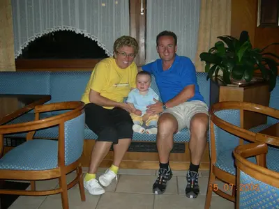 two men and a baby sitting on a couch at B&B La Montanara in San Martino di Castrozza