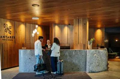 a man and woman standing at a counter in a lobby at Residence Antares in Selva di Val Gardena