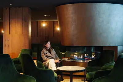 a woman sitting in a chair next to a fireplace at Residence Antares in Selva di Val Gardena