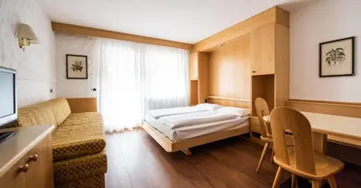 a hotel room with a bed and a table and chairs at Residence Antares in Selva di Val Gardena