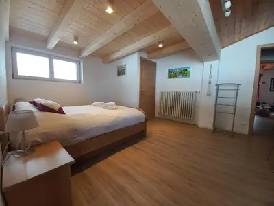 a bedroom with a large bed and a wooden floor at Chalet Relax in Pozza di Fassa