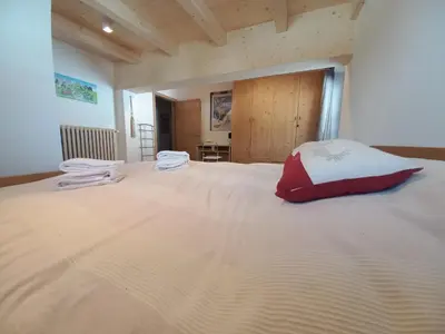 a large white bed with a red pillow on it at Chalet Relax in Pozza di Fassa