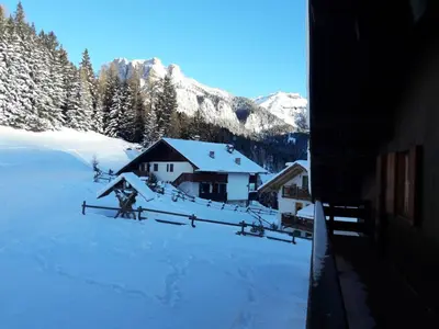 a snow covered yard with a house and a fence at Chalet Relax in Pozza di Fassa