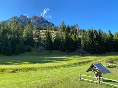 a wooden fence in a field with a mountain at Chalet Relax in Pozza di Fassa