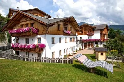 a house on a snowy hill with mountains in the background at Appartement Birkenhof in Maranza