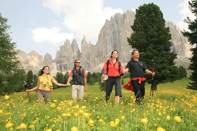 a group of women walking through a field of flowers at Good Life Hotel Zirm in Obereggen