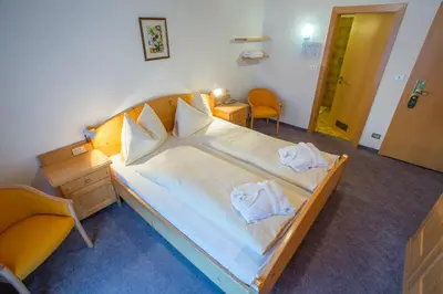a bedroom with a large bed with two towels on it at Good Life Hotel Zirm in Obereggen