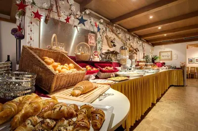 a bakery with a long table with bread and pastries at Good Life Hotel Zirm in Obereggen