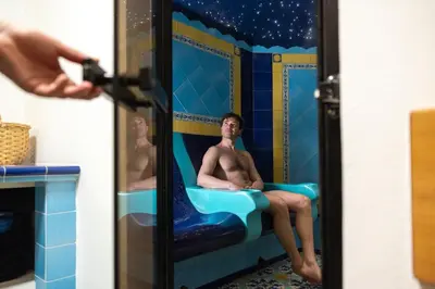a man sitting in a bath tub in a bathroom at Hotel Terme Antico Bagno in Pozza di Fassa