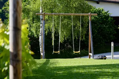 a swing set in a yard with green grass at FORESTO holiday apartments in Tesero