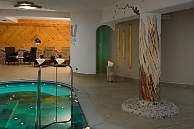 a pool with a tree in the middle of a room at FORESTO holiday apartments in Tesero