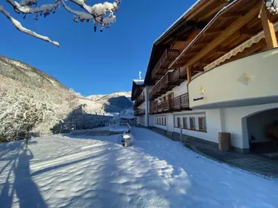 a snow covered street next to a building with a fire hydrant at FORESTO holiday apartments in Tesero