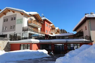 a building in the snow with snow banks in front of it at Alpen Garten Hotel Margherita in Rumo